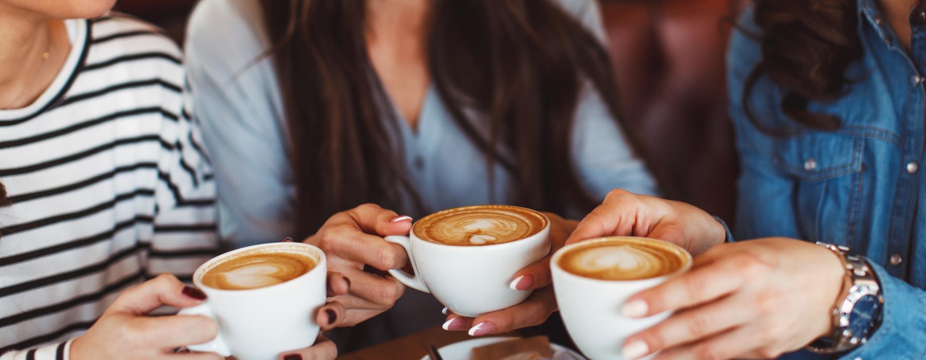 a group of women sitting at a table with cups of coffee